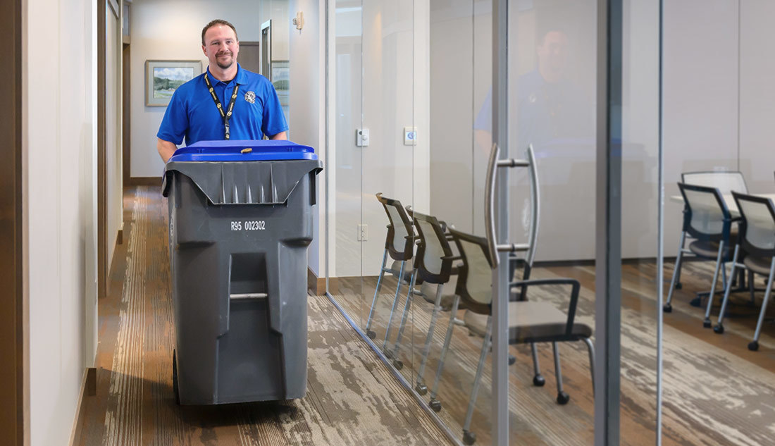 Man carrying bin through office space